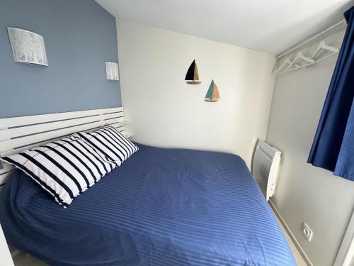 une chambre avec un lit bleu avec un oreiller rayé dans l'établissement Les Glaieuls, à Saint-Gilles-Croix-de-Vie