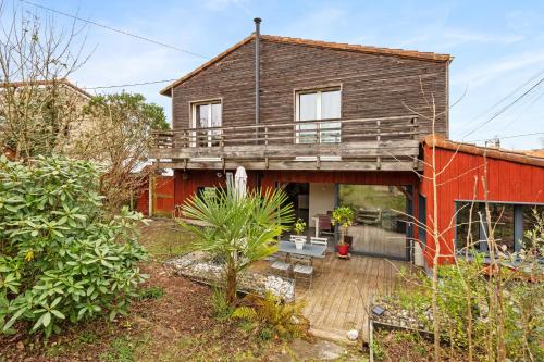 une maison avec une terrasse en bois dans la cour dans l'établissement La Margotte, Maison Charmante et Spacieuse, à Vertou