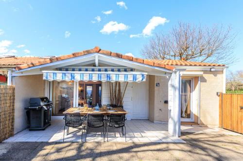 un patio avec une table et des chaises sur un patio dans l'établissement Maison Aturine - Welkeys, à Capbreton