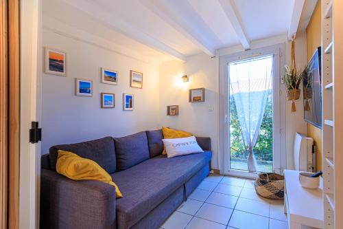 un salon avec un canapé bleu et une fenêtre dans l'établissement Maison Aturine - Welkeys, à Capbreton