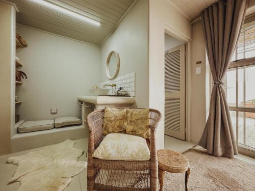 a bathroom with a chair and a sink and a mirror at Buena Vista in Struisbaai in Struisbaai
