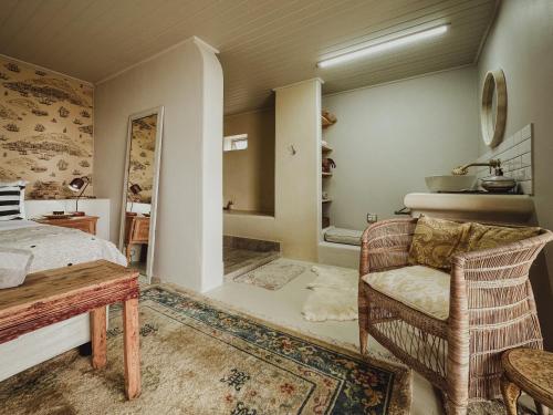 a bedroom with a bed and a chair and a table at Buena Vista in Struisbaai in Struisbaai