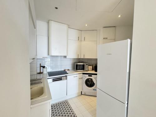 une cuisine avec des armoires blanches et un réfrigérateur blanc dans l'établissement charmante suite vue mer villa Carmela, à Cannes