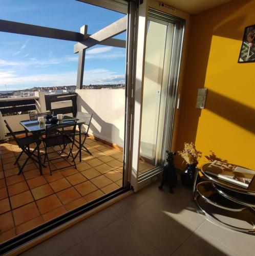 une chambre avec un balcon avec une table et des chaises dans l'établissement Appart 76, Port Nature Colline 2 Village Naturiste, au Cap d'Agde