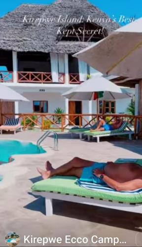 a woman laying on a bed in front of a resort at Kirepwe Ecco Camp Watamu in Watamu