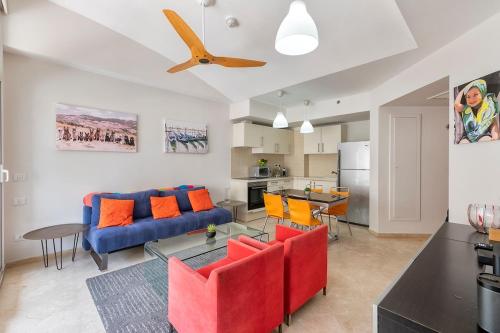a living room with a blue couch and orange chairs at Holiday luxury suite Herzliya marin see view in Herzliyya B