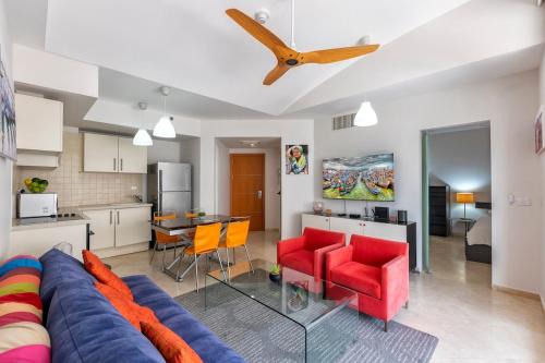 a living room with a blue couch and red chairs at Holiday luxury suite Herzliya marin see view in Herzliyya B