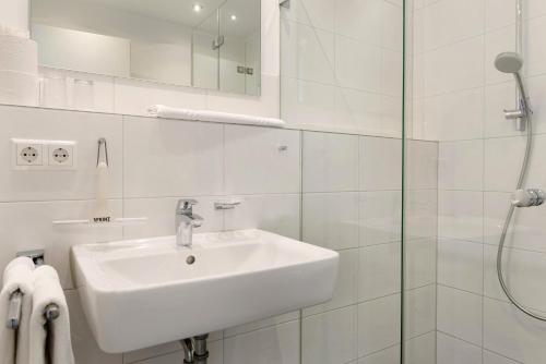 a white bathroom with a sink and a shower at Gästehaus D i c k r e i t e r in Immenstaad am Bodensee