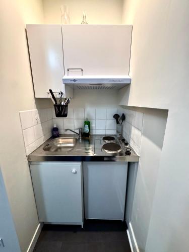 une petite cuisine avec des armoires blanches et un évier dans l'établissement Antoine T2- 2 min Gare- Paisible, à Grenoble