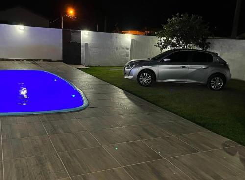 een auto geparkeerd op een oprit met een blauw zwembad bij Praia Grande House in Fundão