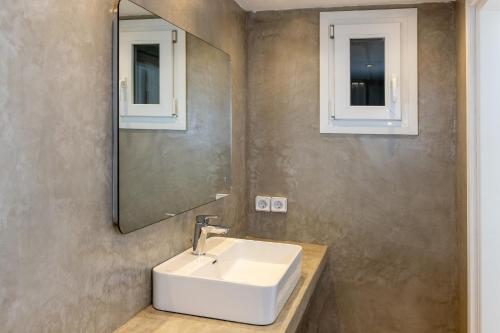 a bathroom with a white sink and a mirror at Villa Marble Tinos in Agios Fokas