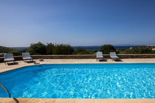 a large swimming pool with two lawn chairs at Villa Marble Tinos in Agios Fokas