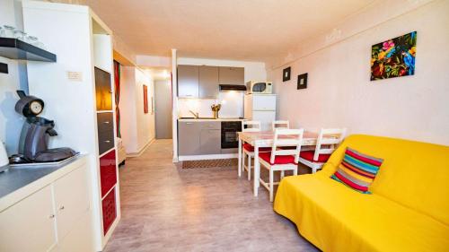 un salon avec un canapé jaune et une cuisine dans l'établissement T2- pied dans l'eau- clim, au Lavandou