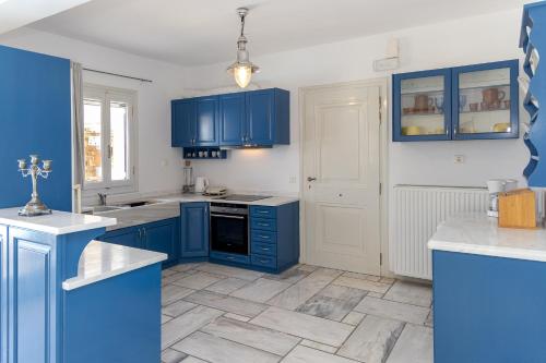 a blue kitchen with blue cabinets and a tile floor at Villa Marble Tinos in Agios Fokas