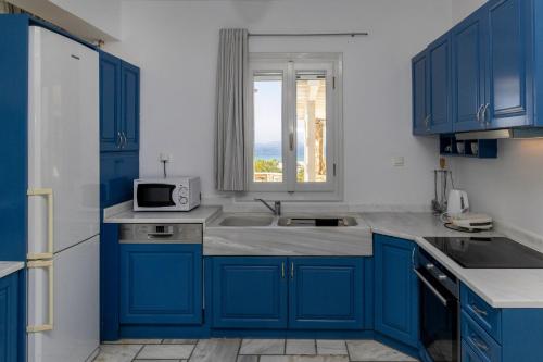 a blue kitchen with a sink and a window at Villa Marble Tinos in Agios Fokas