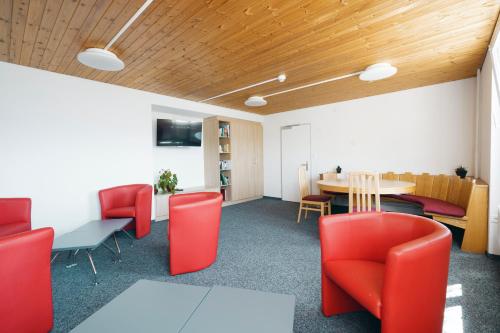 an office with red chairs and a table and a dining room at Schwendihaus Apartment in Amden