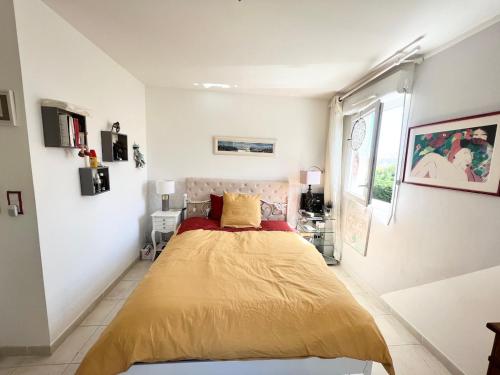 une chambre avec un lit avec une couverture jaune dans l'établissement CHEZ MONNA confort , résidence avec piscine, à La Ciotat