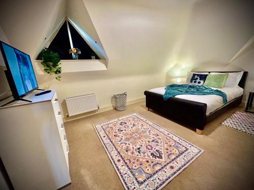 a bedroom with a bed and a television and a rug at 5 Bedroom House- Contractors, Crew, Group, Family in Colchester