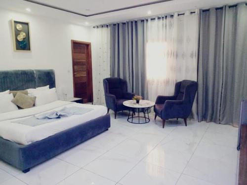 a bedroom with a bed and two chairs and a table at Bi-Hotel 1 in Dakar