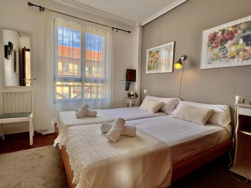 una camera da letto con due letti e una finestra di Duplex Golf El Mirador de Rovacías - Monabri a Comillas