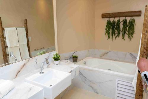 a bathroom with a sink and a tub and a mirror at Bali Mar Hotel in Natal