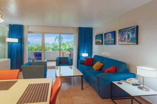 a living room with a blue couch and a table at Sublime Stay - Royal Retreats at Maho Beach in Lowlands