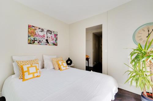 - une chambre avec un lit blanc et une horloge murale dans l'établissement 2P cosy avec terrasse à Neuilly - proche La Défense, à Neuilly-sur-Seine