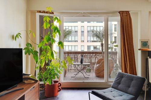 un salon avec un canapé et une grande fenêtre dans l'établissement 2P cosy avec terrasse à Neuilly - proche La Défense, à Neuilly-sur-Seine