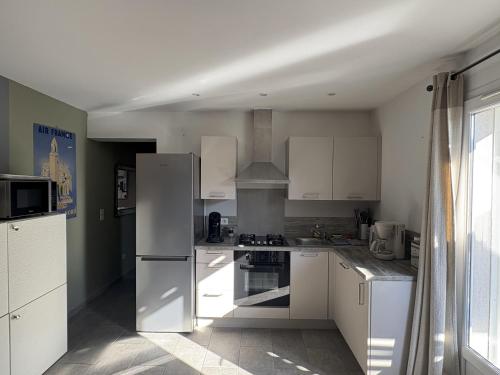 une cuisine avec des appareils blancs et une grande fenêtre dans l'établissement Mini-villa 1, à Bonifacio