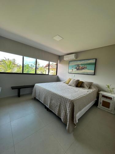 a bedroom with a bed and two windows at House 16 - Reserva dos Carneiros in Tamandaré