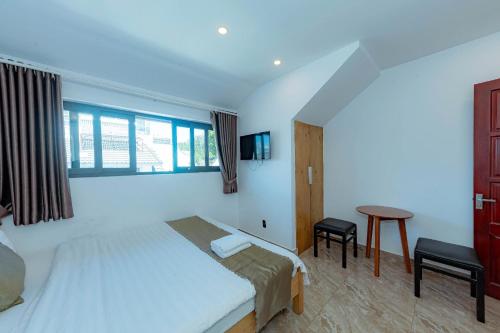 a bedroom with a bed and a table and a window at Sunrise Valley Dalat Hotel in Da Lat