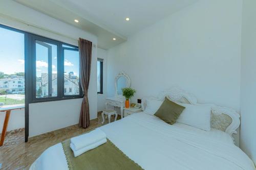 a bedroom with a white bed and a large window at Sunrise Valley Dalat Hotel in Da Lat