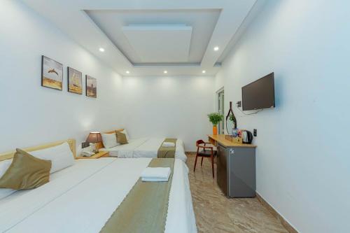 a white living room with a couch and a tv at Sunrise Valley Dalat Hotel in Da Lat