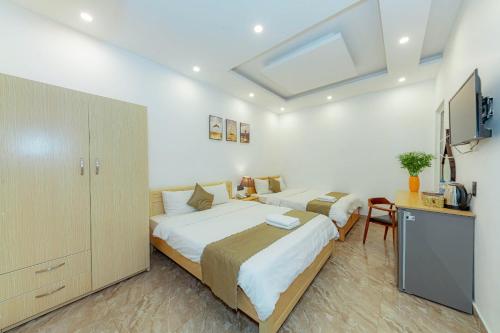 a bedroom with two beds and a desk and a television at Sunrise Valley Dalat Hotel in Da Lat