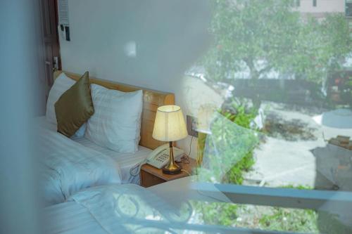 a bedroom with a bed and a lamp and a window at Sunrise Valley Dalat Hotel in Da Lat