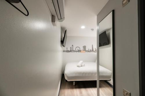 a small bedroom with a bed and a mirror at easyHotel Victoria in London