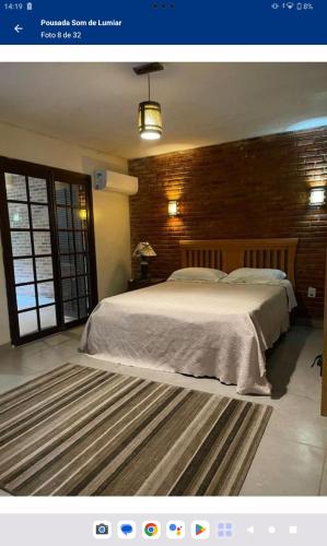 a bedroom with a large bed and a brick wall at Pousada Som de Lumiar in Lumiar