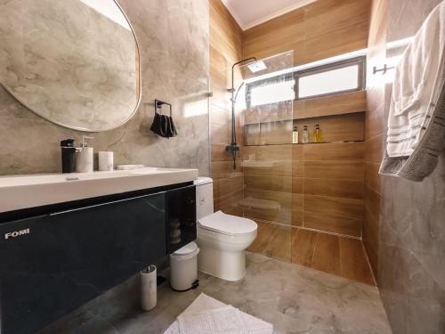 a bathroom with a toilet and a sink and a mirror at Stunning Brand New Villa in Downtown Punta Cana in Punta Cana