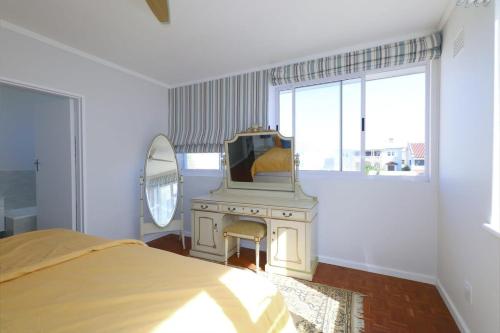 1 dormitorio con cama, espejo y TV en Royal House, en Muizenberg