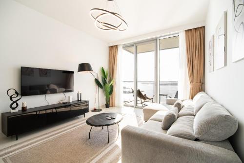 een woonkamer met een bank en een tv bij Beachfront, Perfect sea view, Private beach access, 2-BDR in Dubai