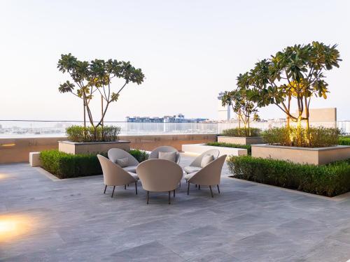 een terras met een tafel, stoelen en bomen bij Beachfront, Perfect sea view, Private beach access, 2-BDR in Dubai