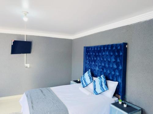 a bedroom with a bed with a blue headboard at Bakwena Lodge in Jane Furse
