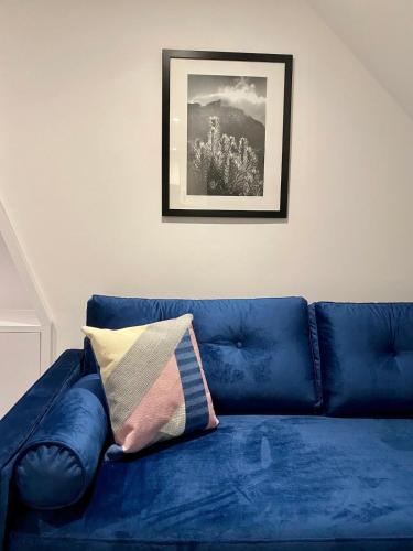 a blue couch in a living room with a picture at Aquila House in Saint Helier Jersey