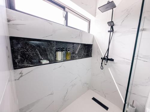 a bathroom with a shower with white marble walls at Stunning Brand New Villa in Downtown Punta Cana in Punta Cana