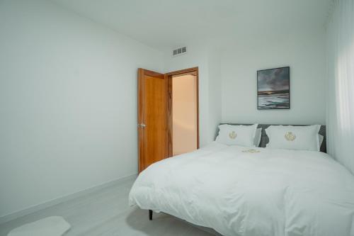 a bedroom with a white bed and a wooden door at Villa Yuka- Luxurious Villa in Eilat