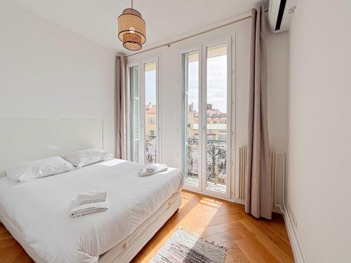 une chambre avec un lit blanc et une grande fenêtre dans l'établissement Escapade en centre ville de Nice - Wifi, AC, 2pers, à Nice
