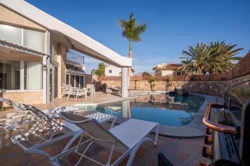 a patio with a table and chairs next to a swimming pool at Villa Yuka- Luxurious Villa in Eilat