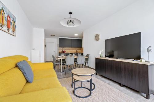- un salon avec un canapé jaune et une télévision dans l'établissement Appartement Amandiers - Welkeys, à Cagnes-sur-Mer