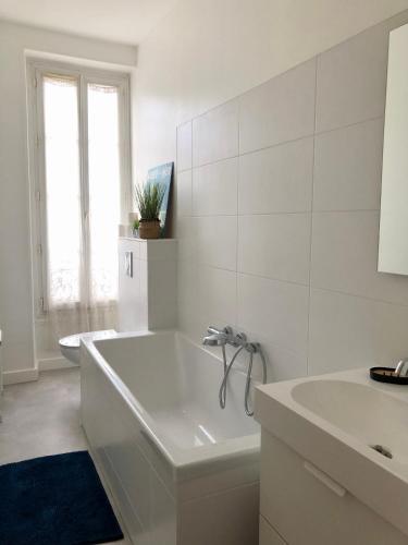 une salle de bain blanche avec une baignoire et un lavabo dans l'établissement Maison familiale équipée, centre-ville, au Mans