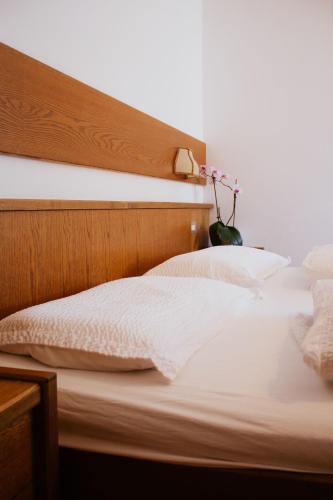 a bed with white sheets and pillows and a vase with flowers at Locanda La Ruscoletta in Telve